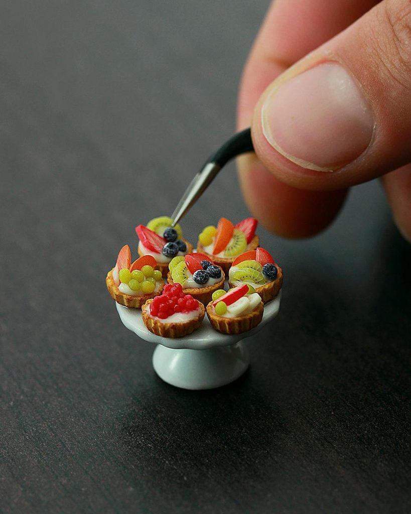 Plate of miniature desserts being arranged with a tweezer.