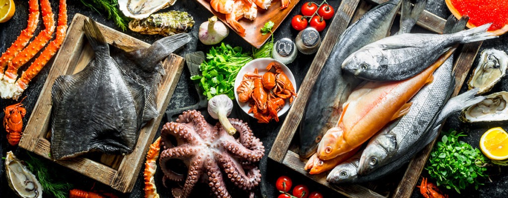 various seafood on a platter - fish, octopus, shrimp and crayfish with herbs