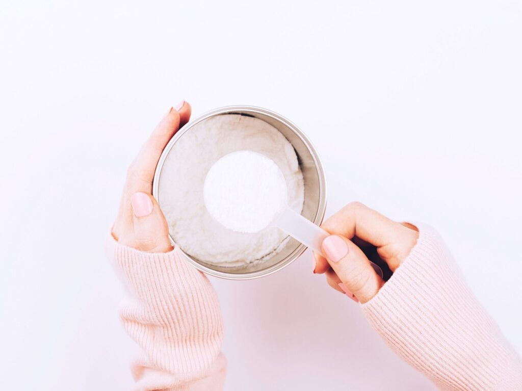 a woman scooping collagen powder out of a container