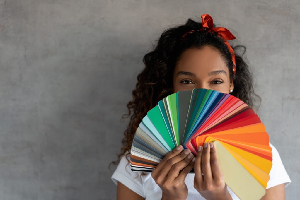 A woman holds a fanned-out set of various color card samples.