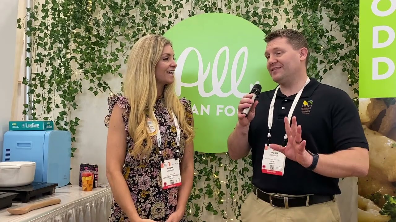 Two people presenting into a microphone at the All Clean Foods booth at Expo West 2022