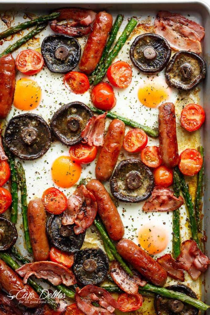 An overhead photo of an example sheet pan breakfast, including mushrooms, carrots, tomatoes, and asparagus